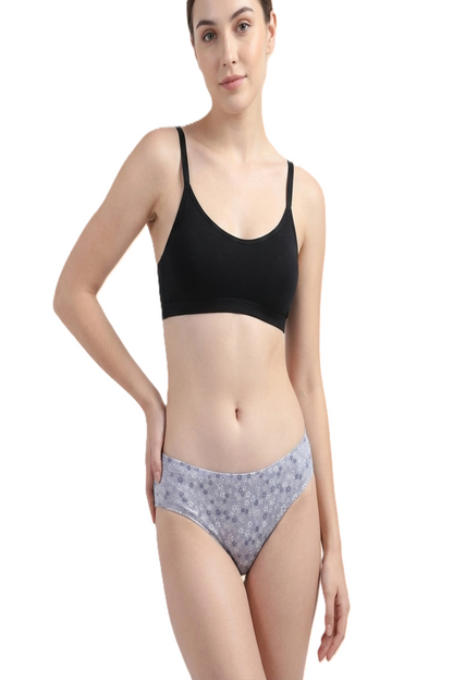 Woman wearing a black bra and gray floral underwear on a white background